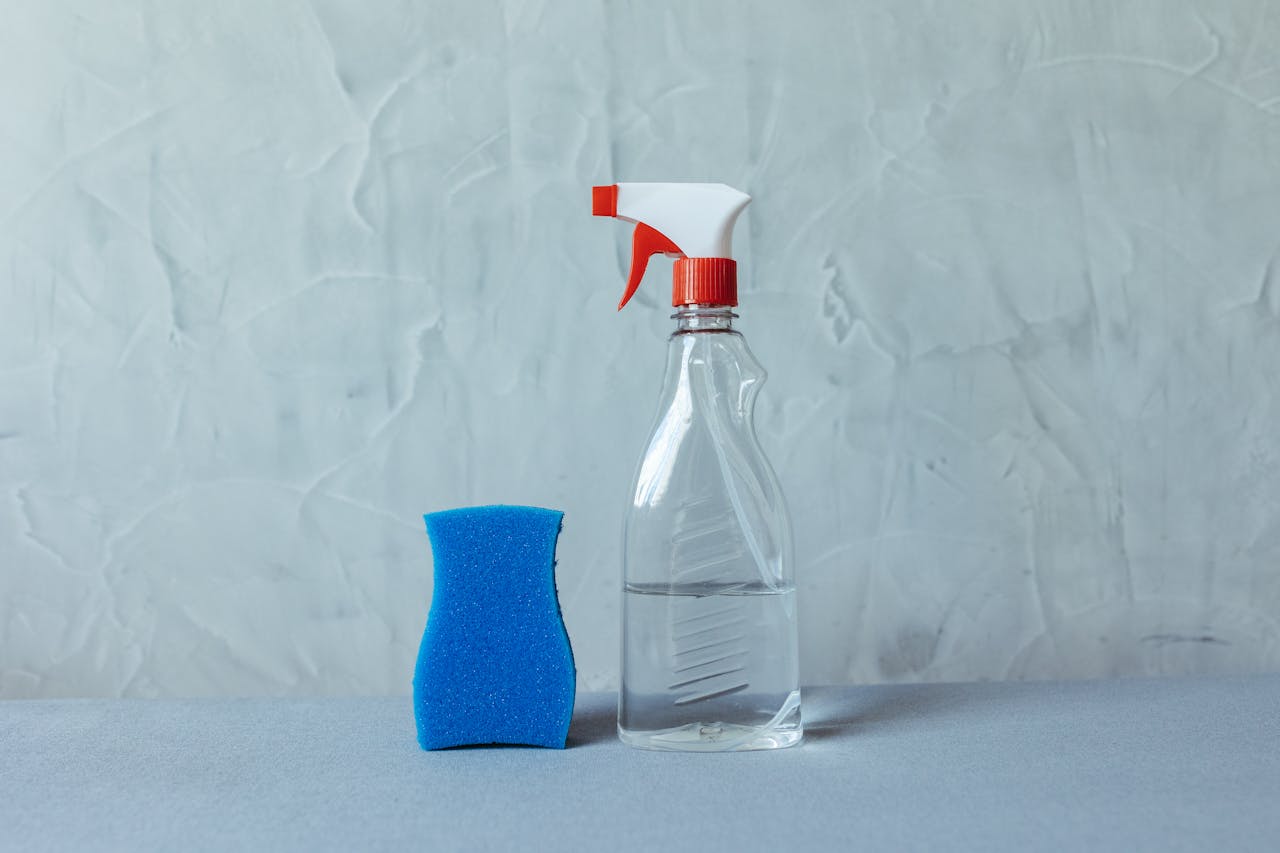services-01 A spray bottle and blue sponge on a textured grey surface. Perfect for cleaning themes.