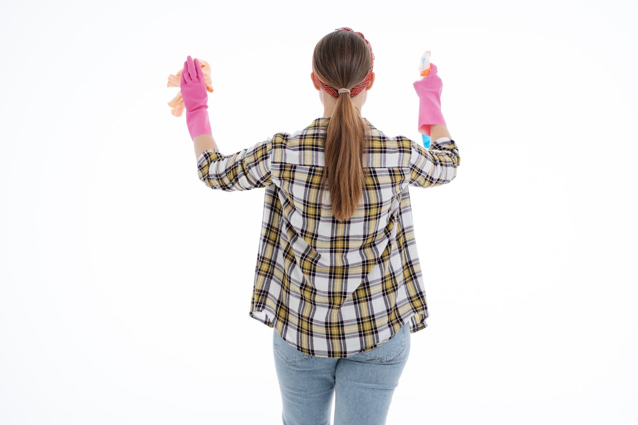 services-02 Back view of a woman in latex gloves cleaning with spray and cloth, indoor studio shot.